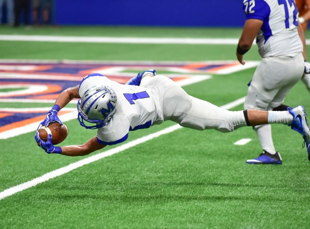 Football player dives to catch the ball