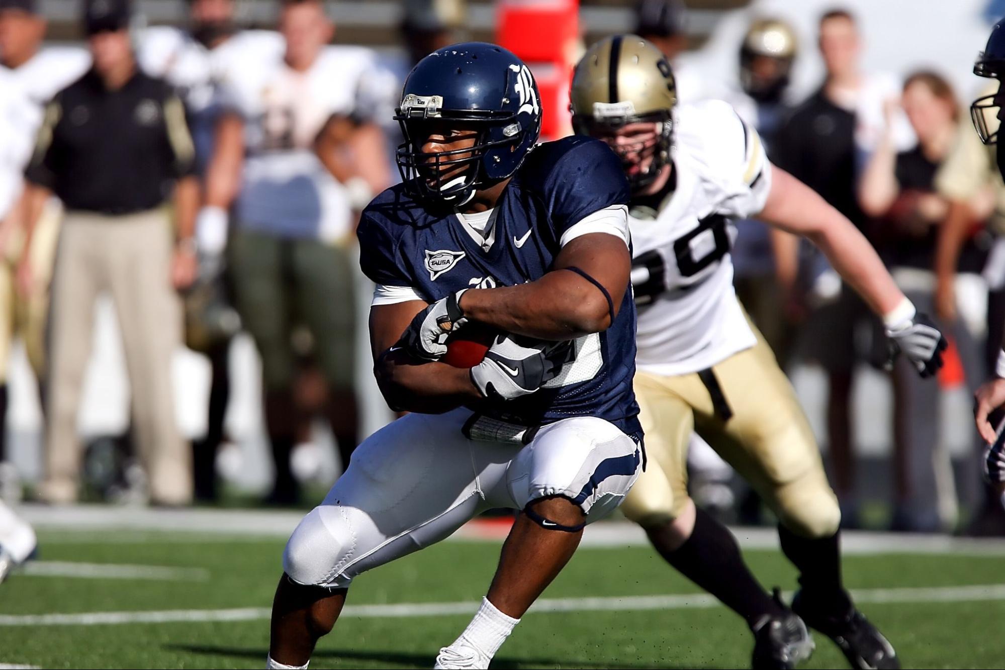 Football player hugging the ball while the opponent is chasing